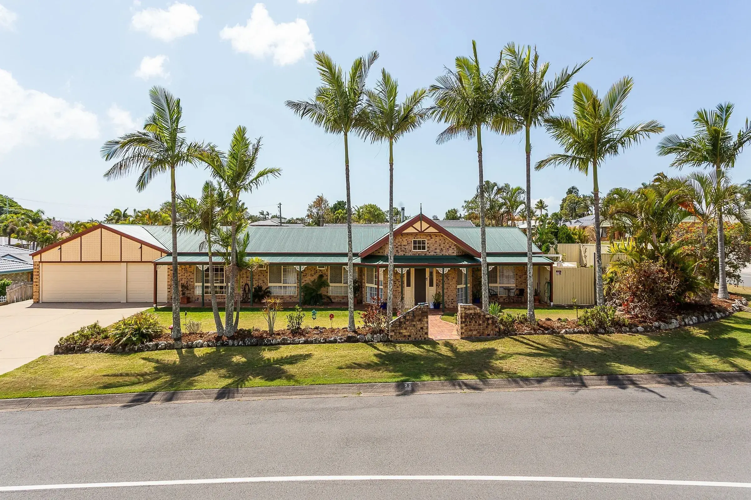 Brick and timber home behind tall palms