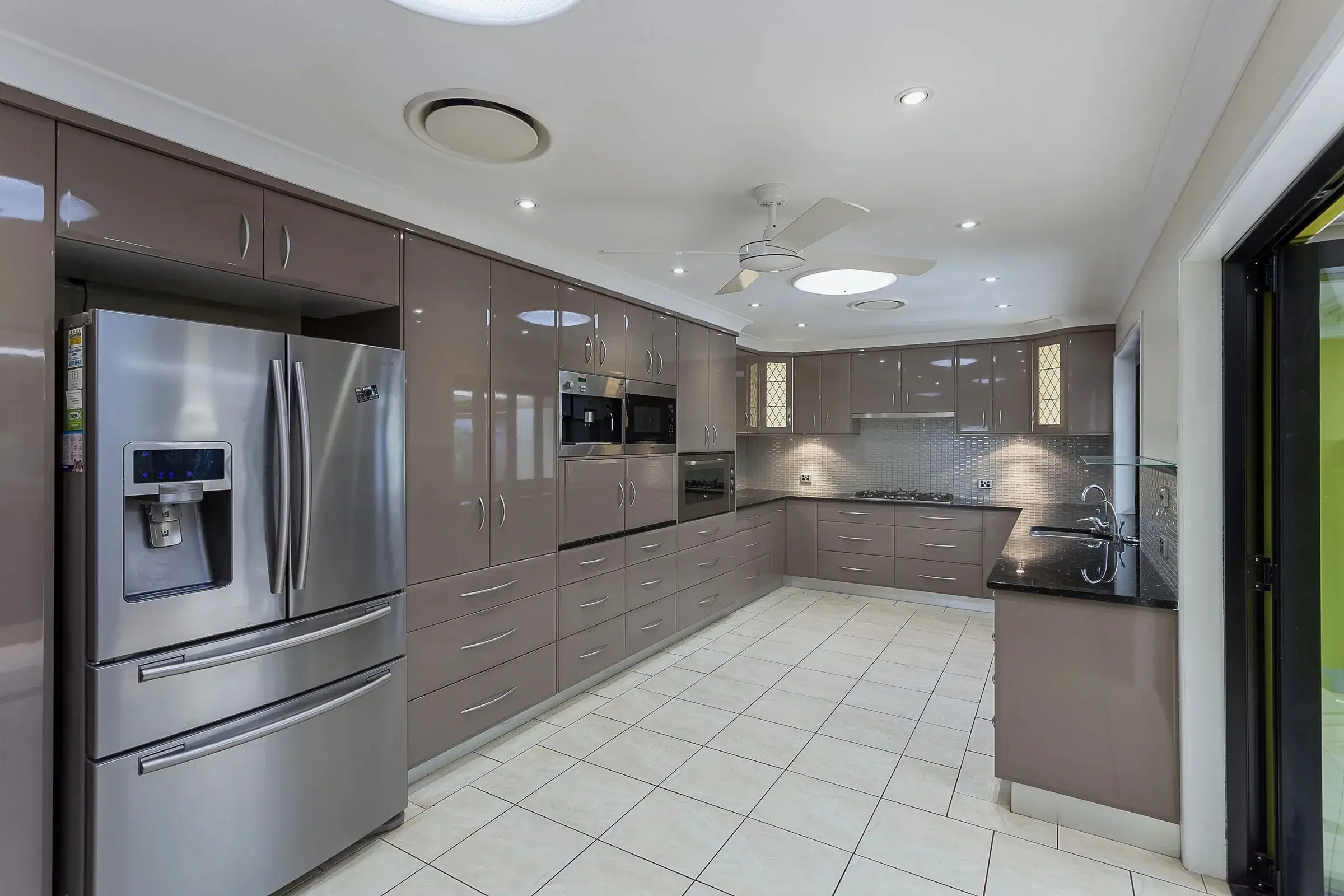 Kitchen with grey gloss cabinets and a double door fridge