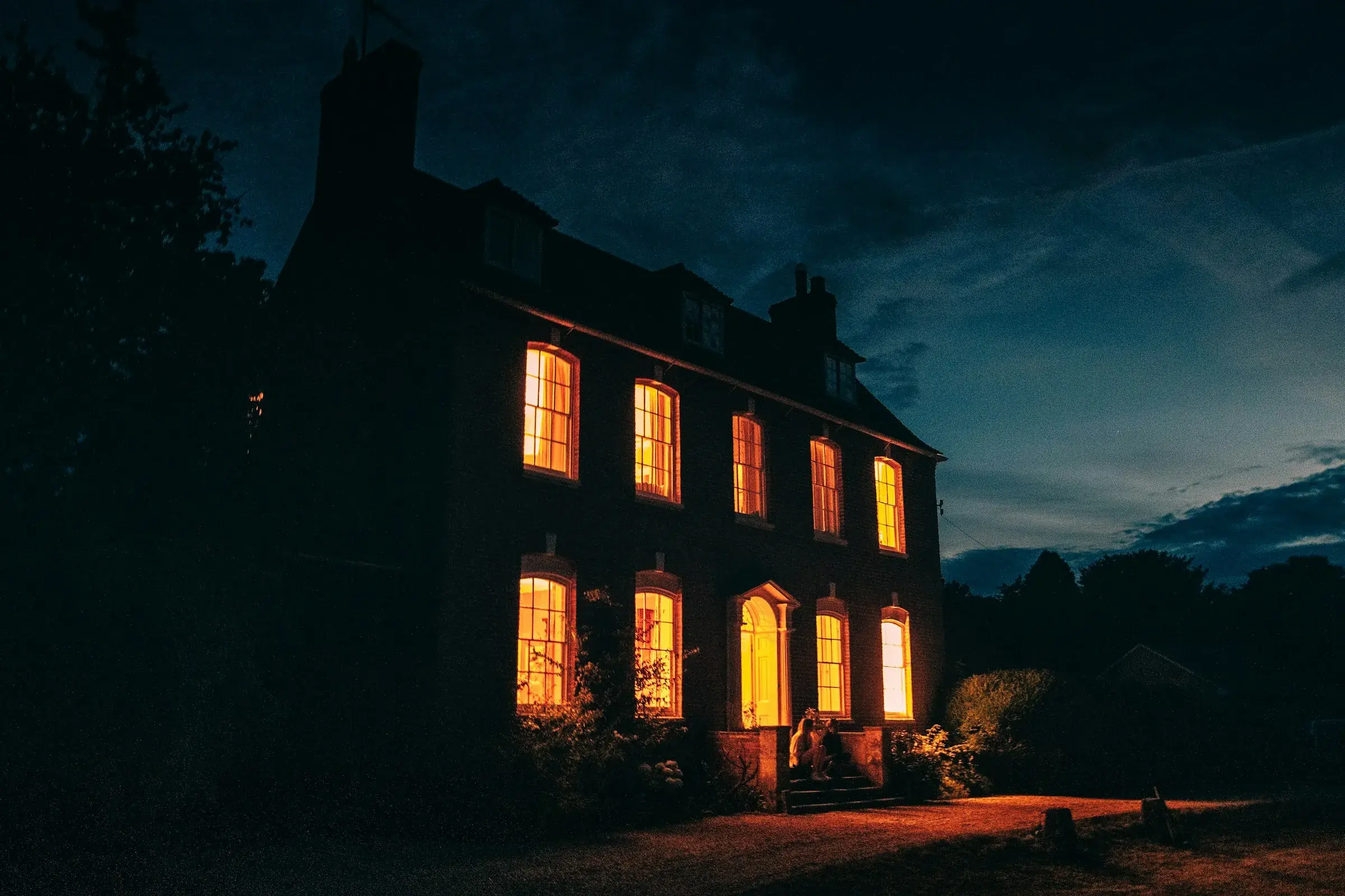 Brick home with every window lit at sunset