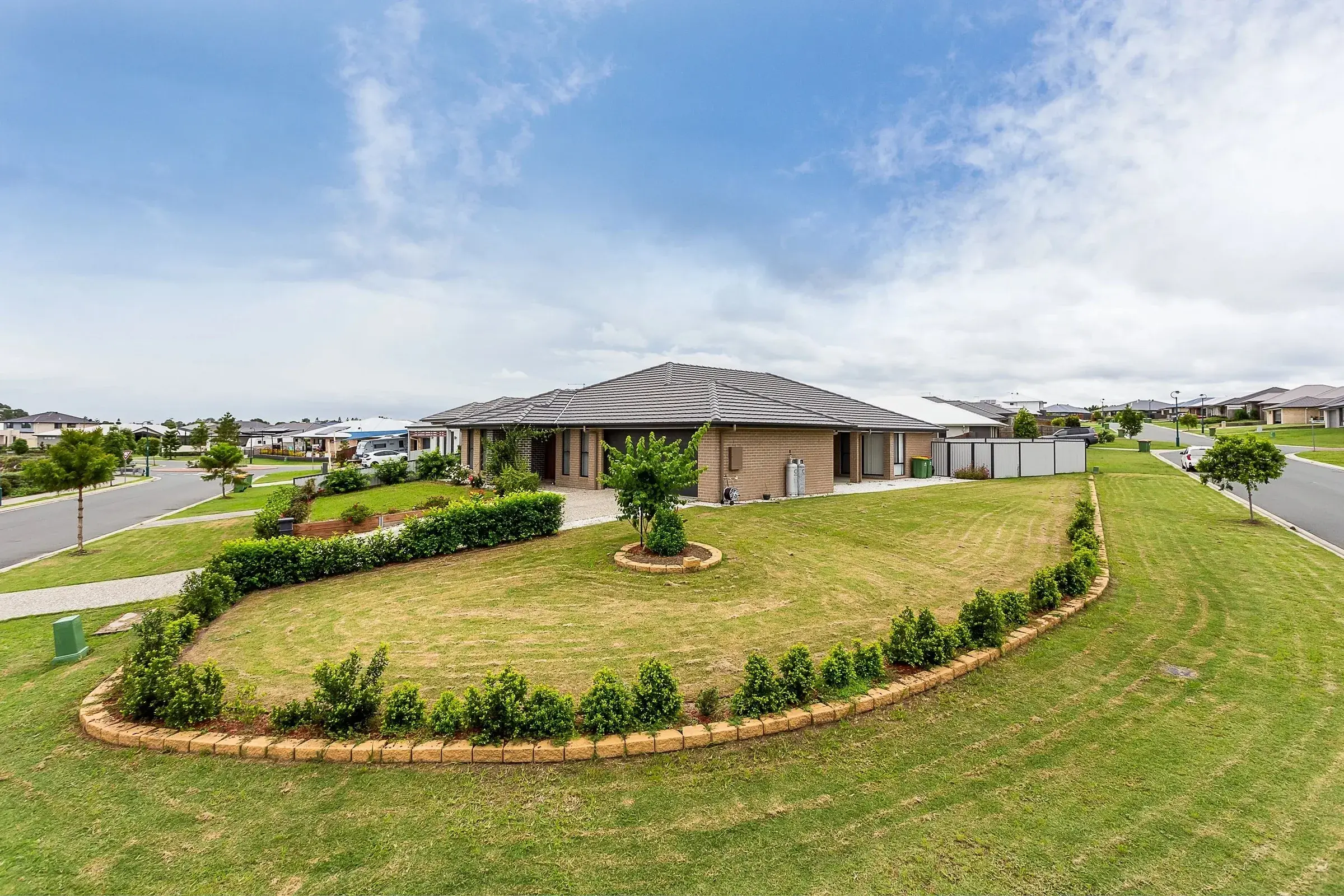 Brick house behind a curved garden bed and wide lawn
